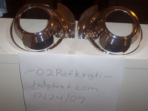 1993 Ford Probe - Two chrome headlight bezels are shown, with handwritten text and a website URL on paper below.