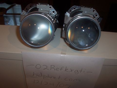 1993 Ford Probe - Two projector headlight assemblies are shown, with a note indicating "-02 Reflexgti - hidplanet.com 12/24/07" and a Supermotors logo.