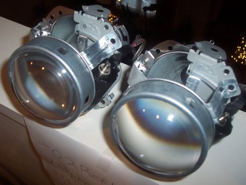 1993 Ford Probe - Close-up of two disassembled headlight assemblies, showing their internal components and clear lenses.