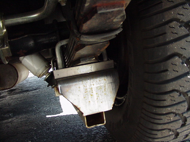 Undercarriage view of rear leaf spring, shackle and bracket next to a tire