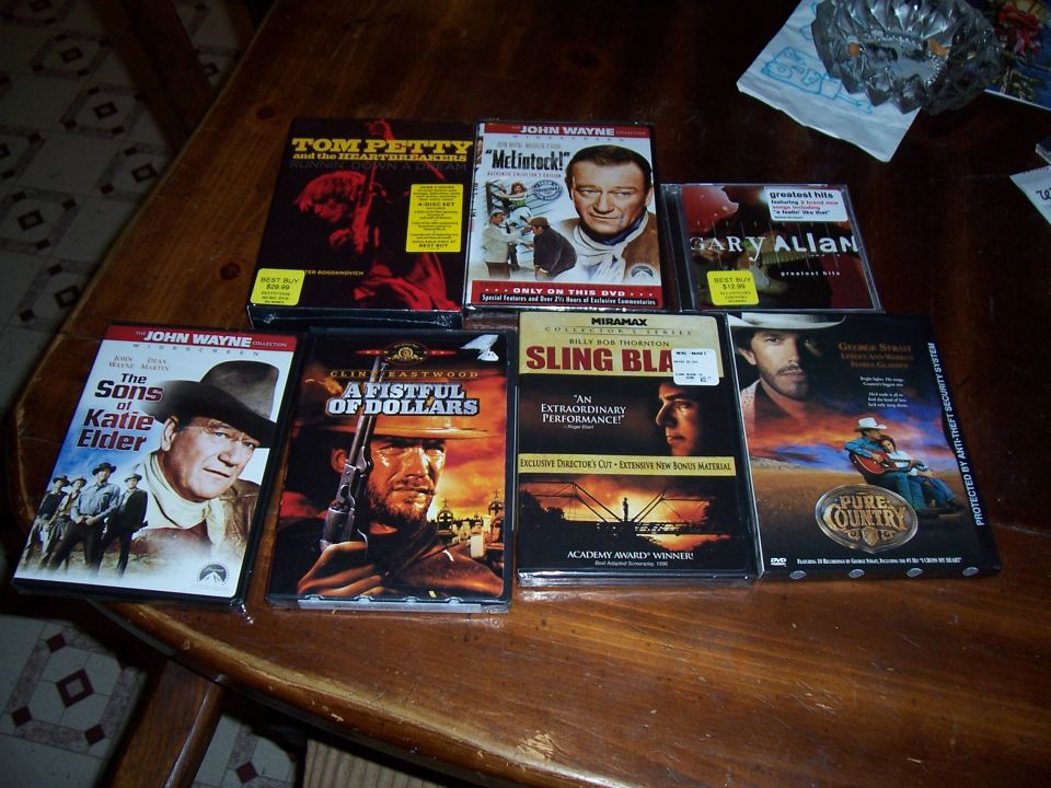 Assorted Western movie DVDs and music CDs arranged on a wood table