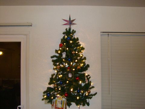 1989 Ford Bronco - A decorated Christmas tree stands against a wall, adorned with lights and ornaments.