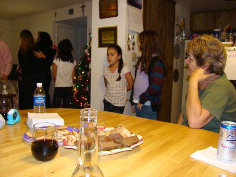 1989 Ford Bronco - A holiday gathering is captured indoors, showing people interacting near a decorated Christmas tree and a table laden with snacks.