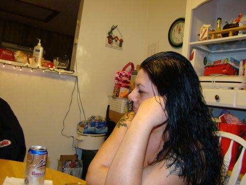 1989 Ford Bronco - A woman with long dark hair and tattoos is seated at a table, with a can of beer in front of her.