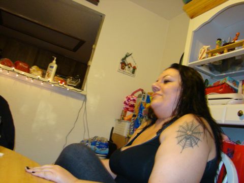 1989 Ford Bronco - A woman with dark hair and a spiderweb tattoo on her shoulder is seated in a room.
