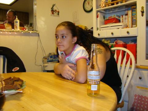 1989 Ford Bronco - A girl sits at a table with a beer bottle and food, while a man is visible in the background.