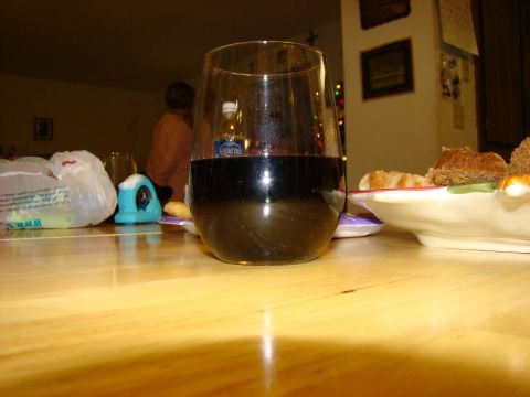 1989 Ford Bronco - A glass of red wine sits on a table, with a blurry background of people and food.
