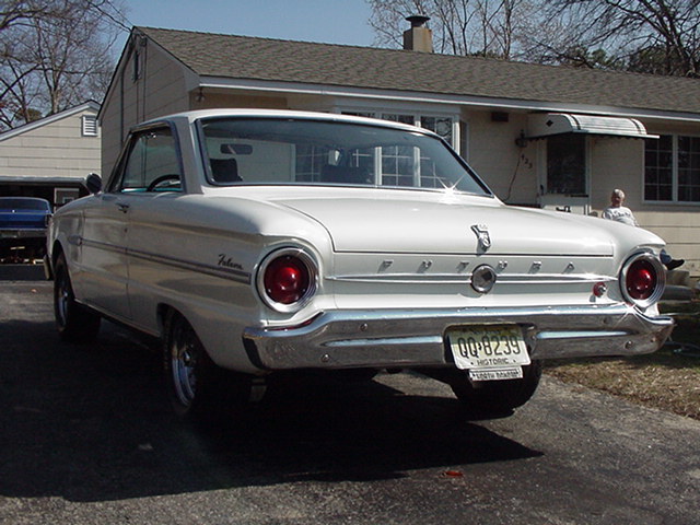 1960 Ford Falcon, rear 3/4 view. Blue car in background. License plate QQ-8239