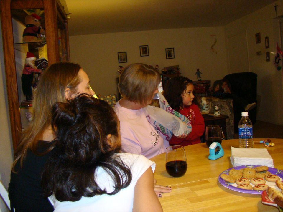 Four people, including two children, sit at a wooden table with cookies and drinks