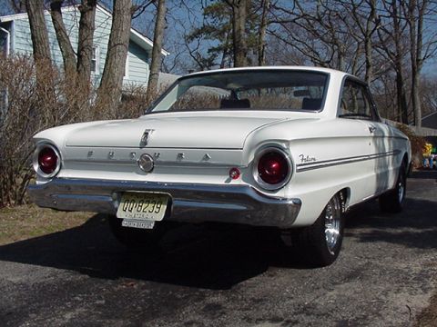 1966 Ford Fairlane - This white 1960 Ford Falcon coupe is viewed from the rear, showing its distinctive taillights and chrome bumper.