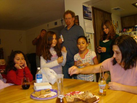 1989 Ford Bronco - A group of people are gathered around a table, some interacting and others looking down at food and drinks.