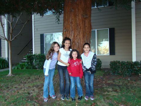 1989 Ford Bronco - Four young girls pose for a photo in front of a large tree and apartment complex.