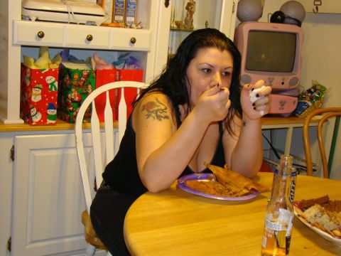 1989 Ford Bronco - A woman eats tamales at a table, with Christmas gift bags visible in the background and a pink television set on a shelf.