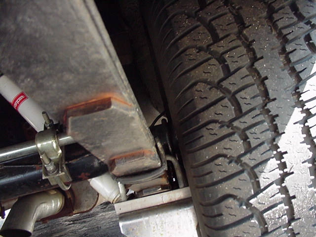 Close-up of a vehicle's leaf spring and tire, showing suspension components and tread detail
