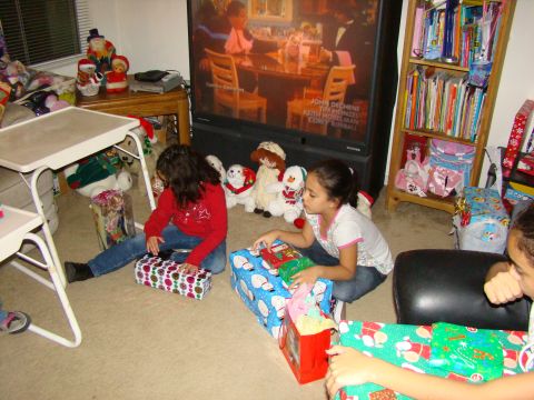 1989 Ford Bronco - Children gather around Christmas presents in a living room, with a holiday movie playing on the television.