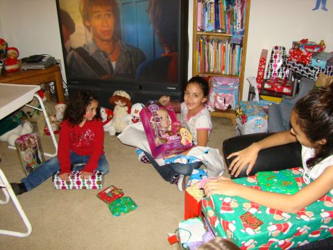 1989 Ford Bronco - Children excitedly open Christmas gifts in a room with a television playing.