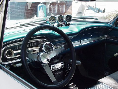 1966 Ford Fairlane - The interior of a 1963 Ford Falcon features a turquoise dashboard, a large steering wheel, and three prominent aftermarket gauges.