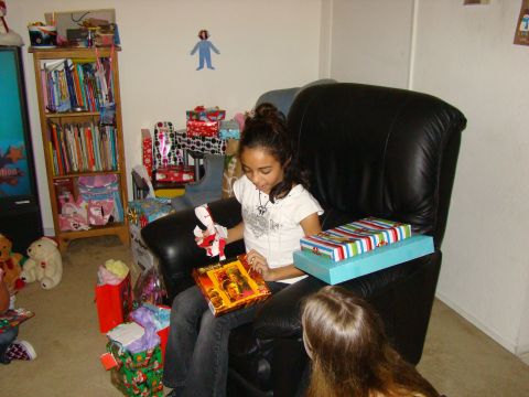 1989 Ford Bronco - A young girl excitedly opens a gift while sitting in a large black chair, with many presents scattered around her.