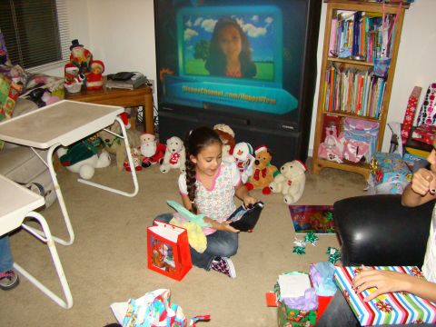 1989 Ford Bronco - A girl opens gifts in a living room decorated for Christmas, with a TV displaying a Disney Channel program.