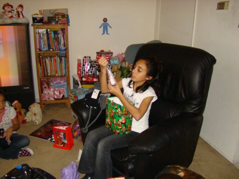 1989 Ford Bronco - A young girl opens a gift while sitting in a recliner, surrounded by presents and a bookshelf.