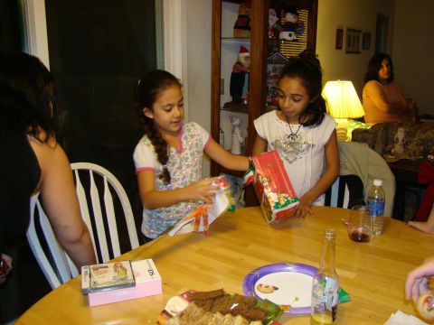 1989 Ford Bronco - A holiday gathering with children eagerly opening presents around a table laden with food and beverages.
