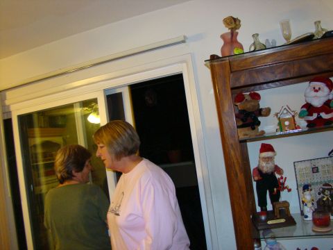 1989 Ford Bronco - Two women converse indoors near a glass door, with a shelf of decorative items visible.