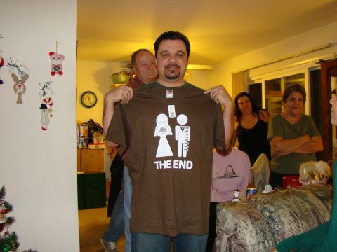 1989 Ford Bronco - A man shows off a t-shirt with a humorous wedding graphic during a holiday gathering.