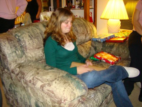 1989 Ford Bronco - A woman sits on a couch, surrounded by wrapped presents, as she opens a gift.