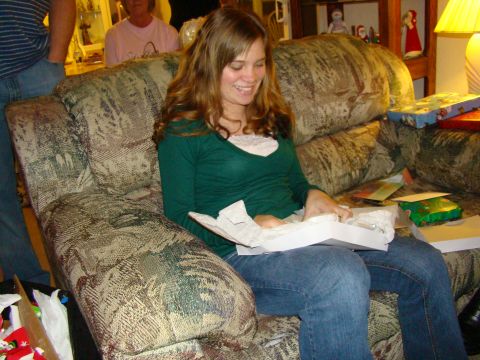 1989 Ford Bronco - A woman smiles as she opens a gift while sitting on a patterned couch, with other people and Christmas decorations in the background.