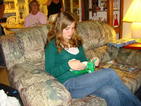 1989 Ford Bronco - A young woman sits on a patterned couch, unwrapping a green gift during a holiday gathering.