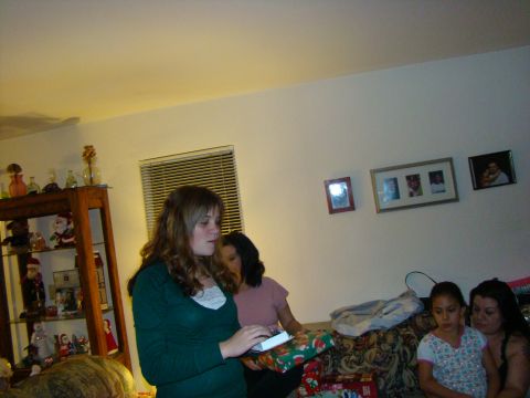 1989 Ford Bronco - A group of people gather in a living room, with some opening gifts during a holiday celebration.