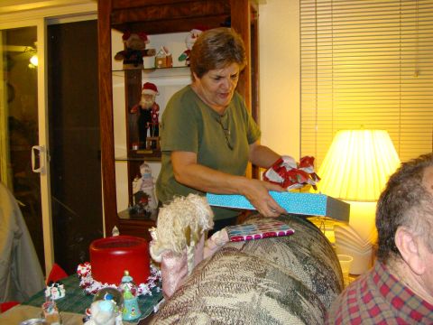 1989 Ford Bronco - A woman opens a Christmas gift while sitting on a couch, with holiday decorations visible in the background.