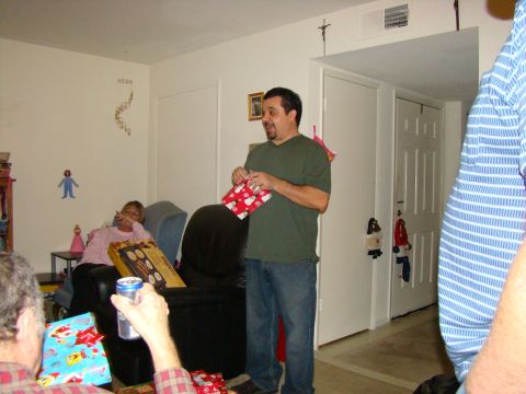1989 Ford Bronco - A group of people are gathered indoors, opening presents during a Christmas celebration.