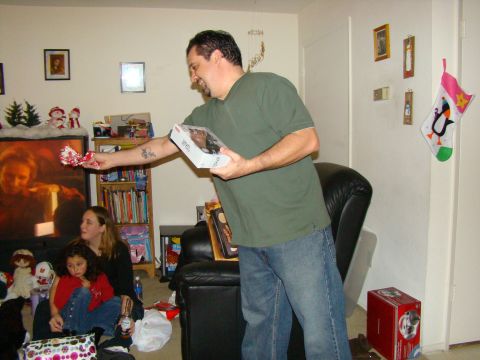 1989 Ford Bronco - A man is giving a gift during a holiday gathering. Christmas stockings hang on the wall.