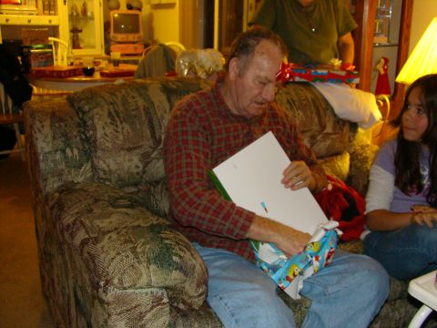 1989 Ford Bronco - A man sits on a couch, opening a Christmas gift while a young girl watches.