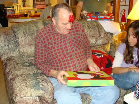 1989 Ford Bronco - A man opens a Christmas gift while a young girl watches. A red bow is on his forehead.