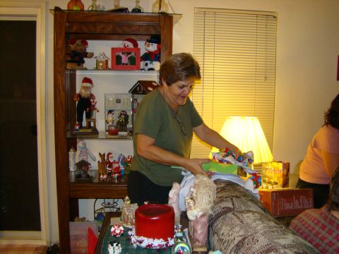 1989 Ford Bronco - A woman unwraps presents in a room decorated for Christmas, with a display cabinet filled with holiday items.
