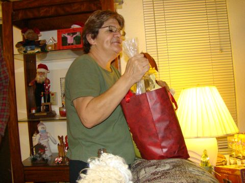 1989 Ford Bronco - A woman is opening a red gift bag in a room with blinds and a lamp.
