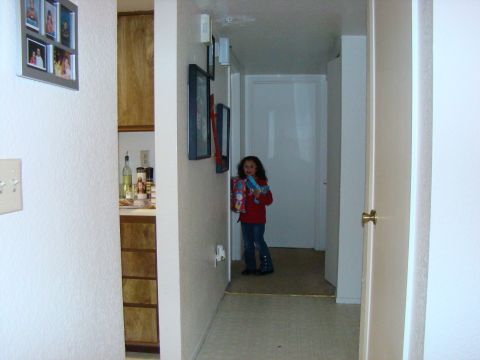 1989 Ford Bronco - A young girl stands in a hallway holding a toy, with framed photos and kitchen cabinets visible in the background.
