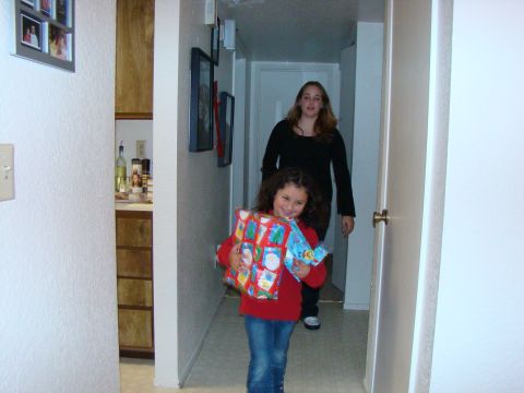 1989 Ford Bronco - A young girl and an adult walk down a hallway carrying wrapped presents.