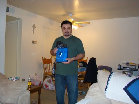 1989 Ford Bronco - A man stands in a living room holding a blue gift bag filled with black tissue paper.