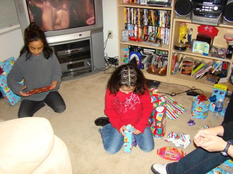 1989 Ford Bronco - Two children unwrap gifts on the floor in a room filled with presents, a television, and entertainment shelves.