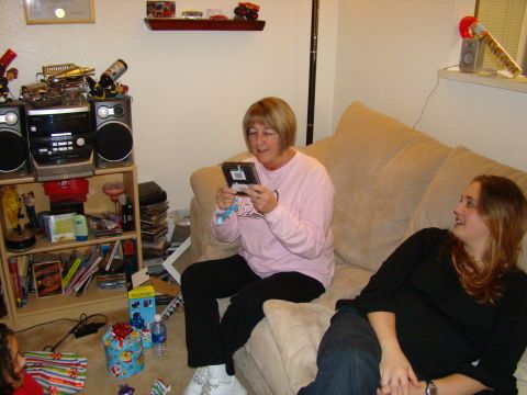 1989 Ford Bronco - Two women are in a living room with gifts on the floor and shelves filled with items.