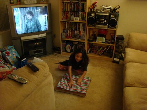 1989 Ford Bronco - A young girl wraps a gift in a living room filled with entertainment items.