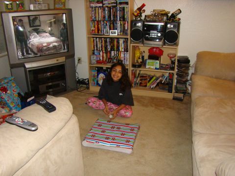 1989 Ford Bronco - A young girl sits on the carpet in a living room, surrounded by entertainment and gifts.