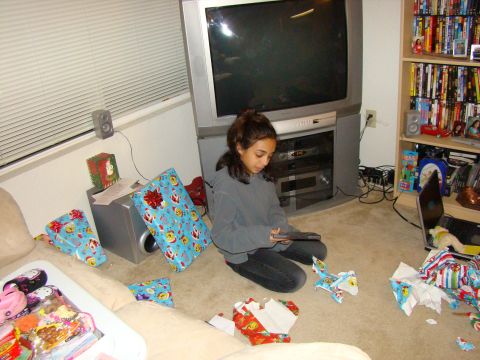1989 Ford Bronco - A girl opens Christmas gifts in a room with a large TV and bookshelves.