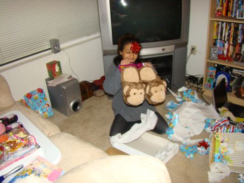 1989 Ford Bronco - A young girl sits on the floor, holding up a pair of novelty monkey slippers after opening presents.