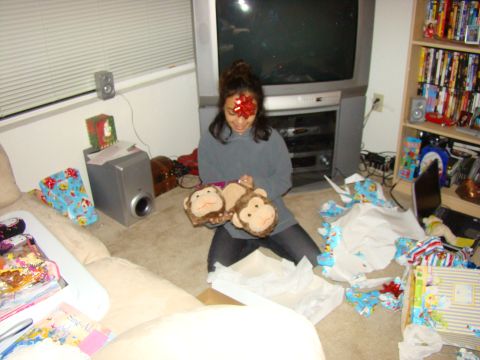 1989 Ford Bronco - Woman opens Christmas gifts, holding stuffed monkeys while sitting near a television and shelves of movies.