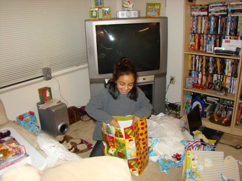1989 Ford Bronco - A young girl excitedly opens a Christmas gift bag surrounded by presents and entertainment media.
