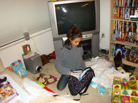 1989 Ford Bronco - A young girl kneels on the floor, unpacking a backpack amidst wrapping paper and presents.